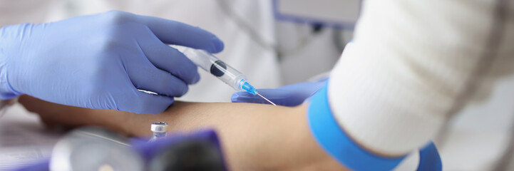 Nurse giving intravenous injection into patient ulnar vein at clinic closeup