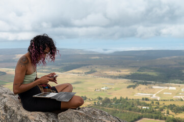 Woman seen sitting on edge of cliff and using mobile phone