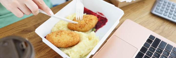 Staff eating cutlets with mashed potatoes from cardboard boxes in office closeup