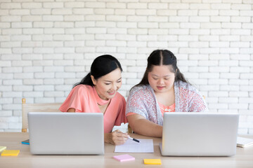 down syndrome teenage girl and her teacher using laptop computer and studying math on a table © offsuperphoto