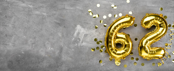 Yellow foil balloon number, number sixty two on a concrete background. Greeting card with the inscription 62. Anniversary concept. for anniversary, birthday, new year celebration. banner,