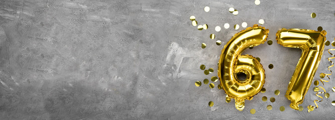 Yellow foil balloon number, number sixty-seven on a concrete background. Greeting card with the inscription 67. Anniversary concept. for anniversary, birthday, new year celebration. banner,