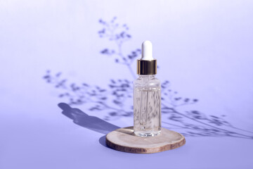 Natural oil cosmetics on violet background. Dropper glass Bottle Mock-Up. Oily cosmetic pipette. Face and body treatment, spa concept. Mineral organic oil. Front view beauty products. Blank bottle