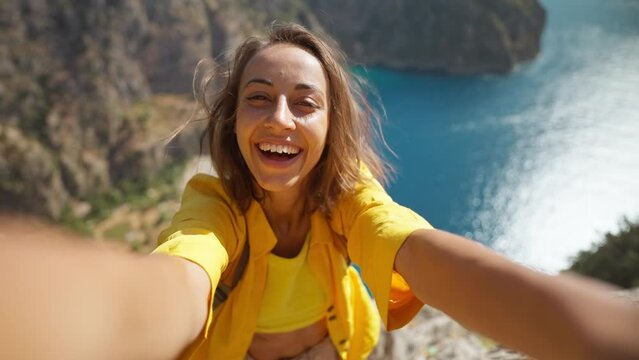Beautiful happy woman making selfie outdoors sharing travel adventure, taking picture for social media, enjoying vacation at Butterfly Valley in Turkey