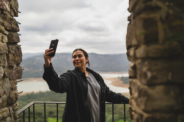 Chica joven guapa en balcon de un pueblo de andalucia tomando selfis con smartphone