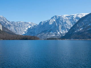 Panoramic view of the crystal-clear Lake Hallstatt. In the background the Dachstein glacier with a cloudless blue sky. Hallstatt, Salzkammergut, Upper Austria. Place for text.
