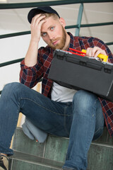 young electrician sitting on stairs indoors