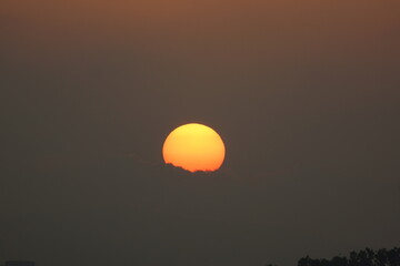 Hazy Sky and orange sunrise through the clouds