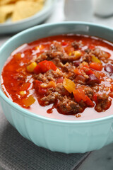 Bowl with tasty chili con carne on table, closeup