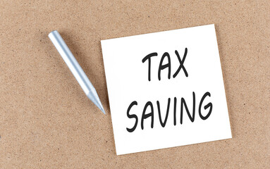 TAX SAVING text on sticky note on cork board with pencil ,