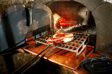 the chef puts the wet-aged steak in the stone oven 
