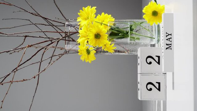 May 22. wooden calendar for May month. The hand changes, puts a wooden cube with the date. Changeable calendar on the table with the month of May. Important date, holiday, event