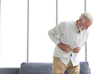 senior man have a stomachache and holding stomach on sofa