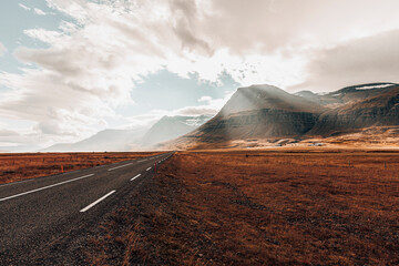 Magical and surreal landscape with road leading to sunlit mountains