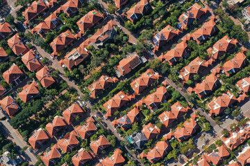 Classic Suburban houses with red rooftops and green trees.