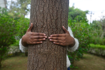 Close up a young kid protecting a huge tree. Concept for love and protect nature.