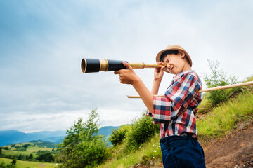 Little boy looking into a vintage retro spyglass. Adventure, travel, pirate game. © Olha