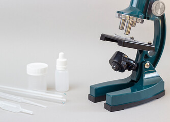 microscope, bottles and test tubes on a gray background