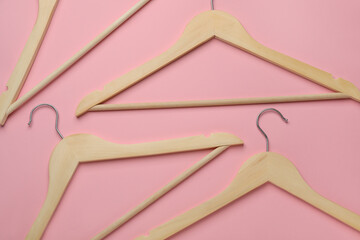 Empty wooden hangers on pink background, flat lay