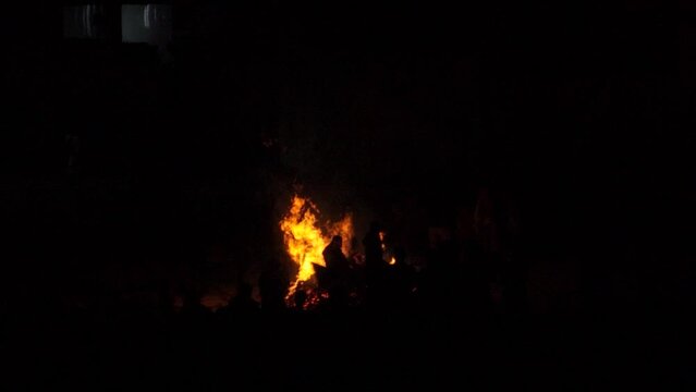Slow motion shot of large bonfire during the Holi or Holika Dahan festival in India. Silhouette of people visible watching the bonfire at lohri festival. People enjoying lohri in India.	
