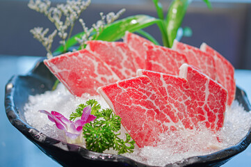 sliced frozen wagyu beef for hot pot on ice in black bowl