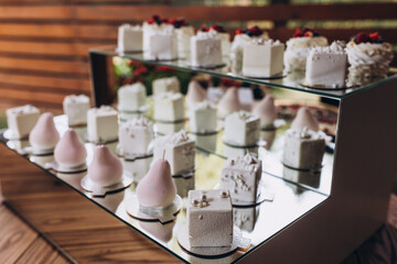 Wedding. Candy bar. On the buffet table there are glasses with desserts from fruits and cream, strawberries in chocolate and sweets.