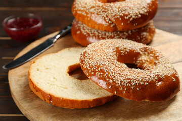 Delicious fresh bagels with sesame seeds on wooden table, closeup