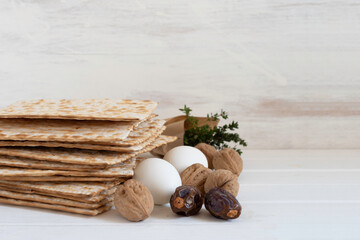 Symbolic meal for Jewish holiday Pesach. Walnuts, date fruits, eggs, matzah on white wooden...