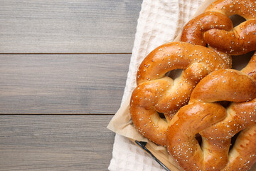 Delicious pretzels with sesame seeds on wooden table, top view. Space for text