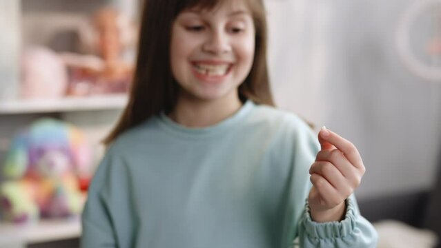 Happy Cute little girl with tooth first milk temporary tooth. Children's hands shows. Tooth change in kid 6-8 years old. Dental medicine or temporary teeth healthcare concept