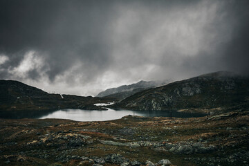 landscape with clouds over the mountains and little lake in norway 