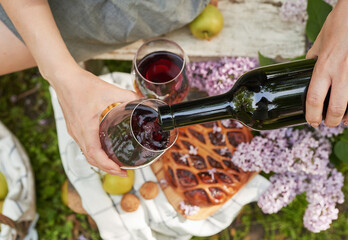 Summer picnic in garden. Wine, pie, fruits and flowers. Still life. Easter lunch and table. Woman's...