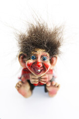 Little cute funny colorful norwegian troll figurine on a white background.