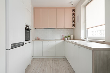 Kuchnia w minimalistycznym nowoczesnym stylu. Białe i różowe fronty mebli oraz sprzęt. Biała lodówka - obrazy, fototapety, plakaty