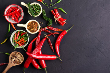 cayenne pepper and fresh red chili and peppers with spices on a dark black background table in a rustic kitchen There is space for text design. - top view