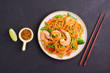 Stir-fried spaghetti or stir-fry noodles with vegetables and shrimp in a black bowl. dark background, top view