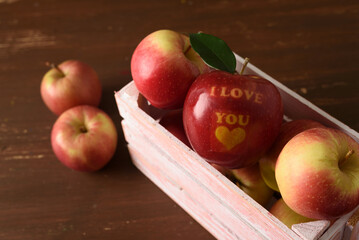 Red apple with text I Love You in wooden crate on table