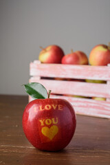 Red apple with text I Love You in wooden crate on table