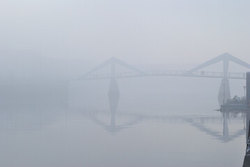 Bridge and Reflections in Still River Water on Misty Morning 