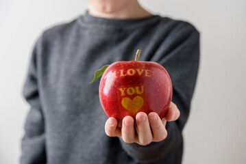 Child holding red apple with text I Love You as gift