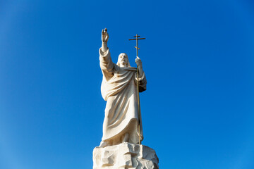 Fototapeta premium Statue of Jesus against a bright blue sky on a sunny day. Rio de Caucasus in Essentuki. Religion and faith.