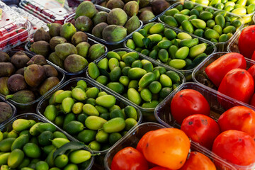 Bright juicy fruits on the counter in the market. Figs, feijoa and persimmon. Close-up. Vitamins and healthy food.