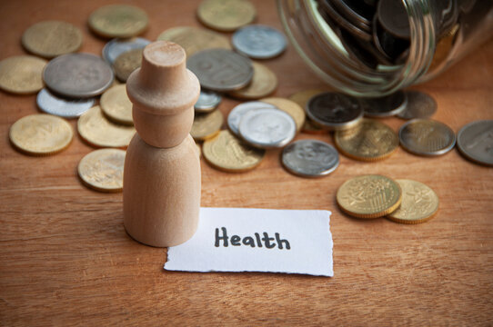Health text on torn paper with jar, coins, and wooden doll model background. Health concept