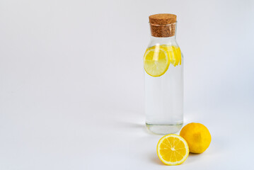 Fresh lemon water in glass bottle with wooden cap on isolated white background