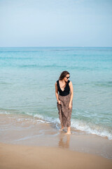 Pretty woman walking with bare feet on sandy beach