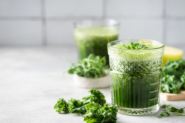 Vegan Green detox juice or smoothie in glass on grey concrete kitchen table. Copy space for text or...