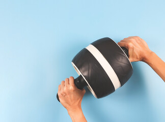  woman's hands using abdominal roller wheel for working out abdominals. blue background. Focus on...