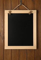 Clean small black chalkboard hanging on wooden wall