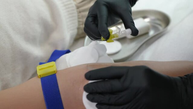 Hands of nurse in gloves insert catheter needle into the hand of the victim. Doctor prepares the patient's hand for blood test or drip close-up