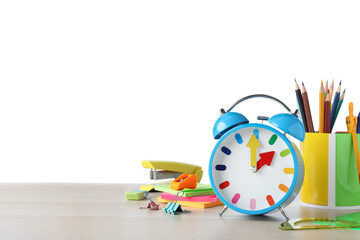 Light blue alarm clock and different stationery on wooden table against white background, space for text. School time